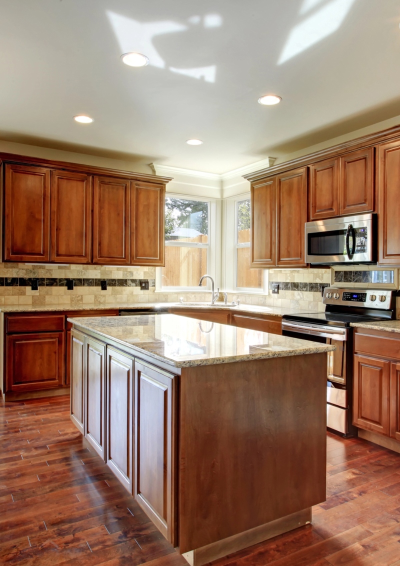 1 Spacious kitchen with dark wood cabinets, a large island with granite countertops, and a view of the backyard through sliding glass doors
