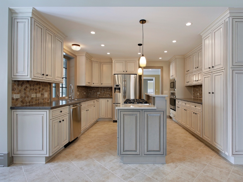 Spacious kitchen with white cabinets, a large island with a white countertop, stainless steel appliances, and a tiled backsplash