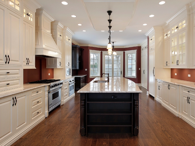 Kitchen with white cabinets, a large island, and a dark wood floor